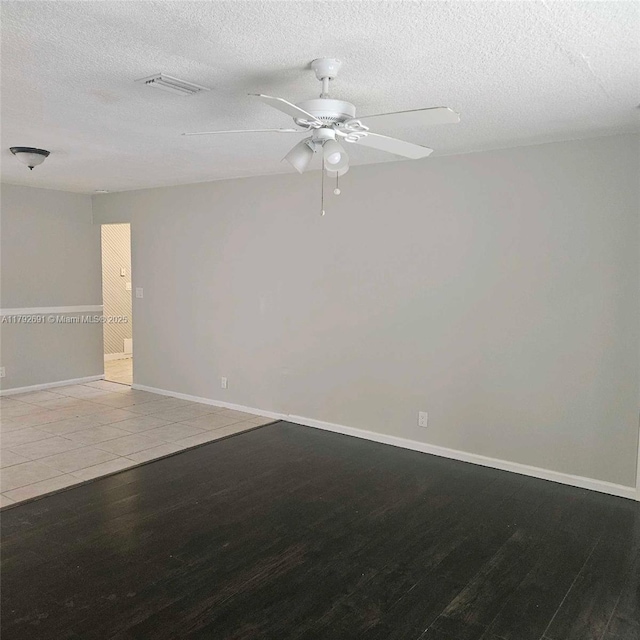 unfurnished room featuring a textured ceiling, a ceiling fan, baseboards, wood finished floors, and visible vents