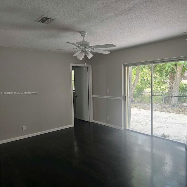 empty room featuring ceiling fan, dark wood-style floors, a textured ceiling, and visible vents