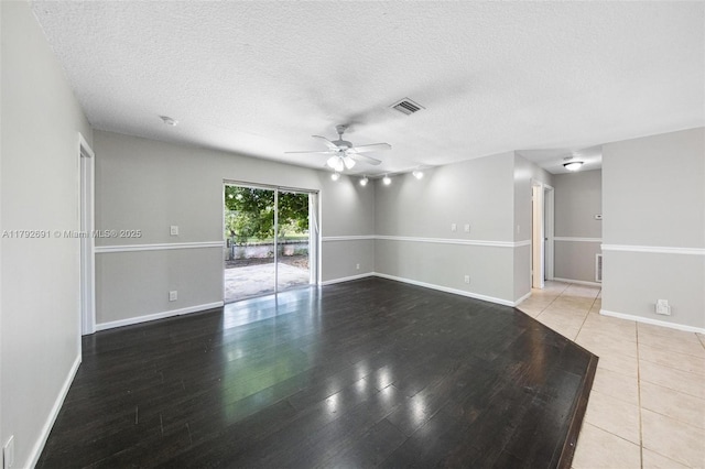empty room with ceiling fan, a textured ceiling, visible vents, wood finished floors, and baseboards