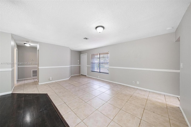 spare room featuring baseboards, a textured ceiling, light tile patterned floors, and visible vents