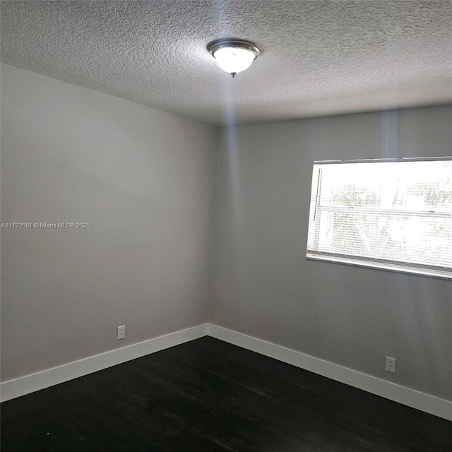 unfurnished room featuring a textured ceiling, baseboards, and dark wood-style floors