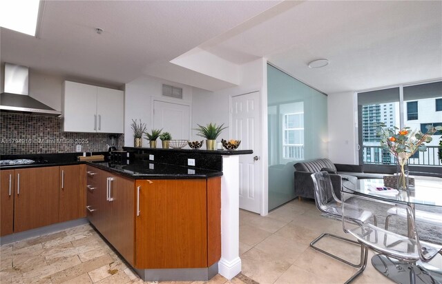 170 SE 14th St Unit 2708, Miami, FL 33131 - kitchen featuring wall chimney exhaust hood, dark stone counters, a peninsula, tasteful backsplash, and visible vents