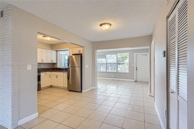7740 Shalimar St, Miramar, FL 33023 - kitchen featuring a textured ceiling, dark countertops, light tile patterned floors, baseboards, and freestanding refrigerator
