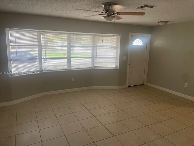 empty room featuring baseboards, ceiling fan, a textured ceiling, and visible vents