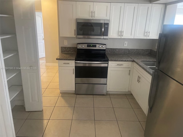 kitchen featuring white cabinetry, appliances with stainless steel finishes, light tile patterned floors, and dark countertops
