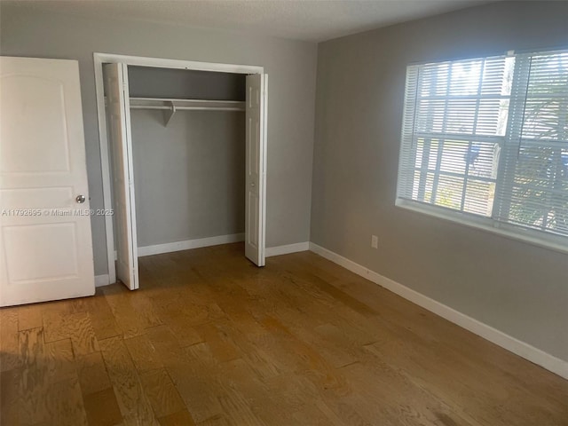unfurnished bedroom featuring baseboards, a closet, and wood finished floors
