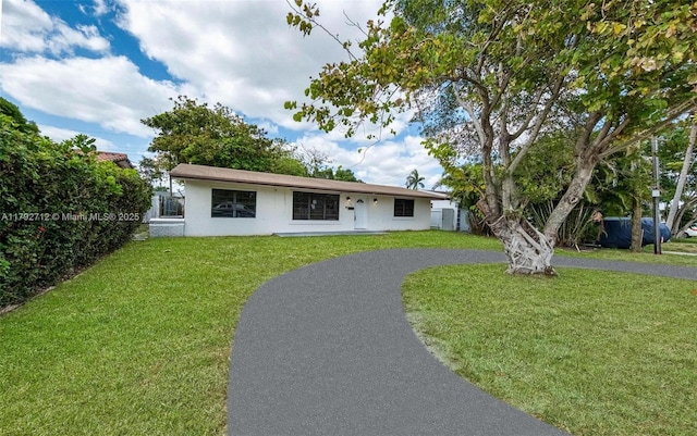 7817 NE Madeira St, Miramar, FL 33023 - single story home with aphalt driveway, a front yard, and stucco siding