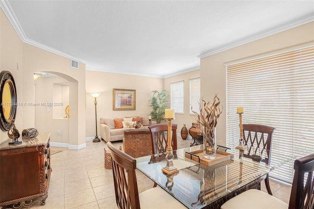 dining room featuring arched walkways, baseboards, light tile patterned floors, visible vents, and ornamental molding