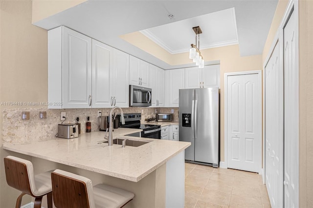 kitchen featuring light stone counters, a sink, stainless steel appliances, a peninsula, and backsplash