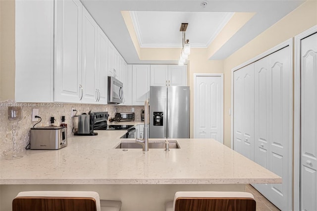 kitchen with ornamental molding, decorative backsplash, a peninsula, white cabinets, and appliances with stainless steel finishes
