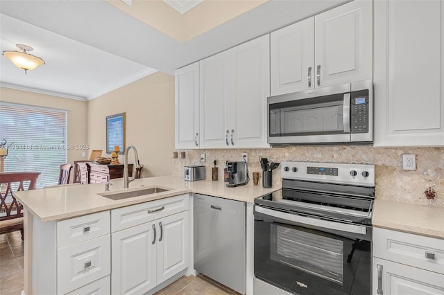 kitchen featuring crown molding, a peninsula, tasteful backsplash, a sink, and stainless steel appliances