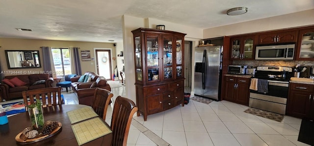 8111 SW 205th St, Cutler Bay, FL 33189 - kitchen featuring decorative backsplash, dark brown cabinetry, appliances with stainless steel finishes, light tile patterned floors, and glass insert cabinets