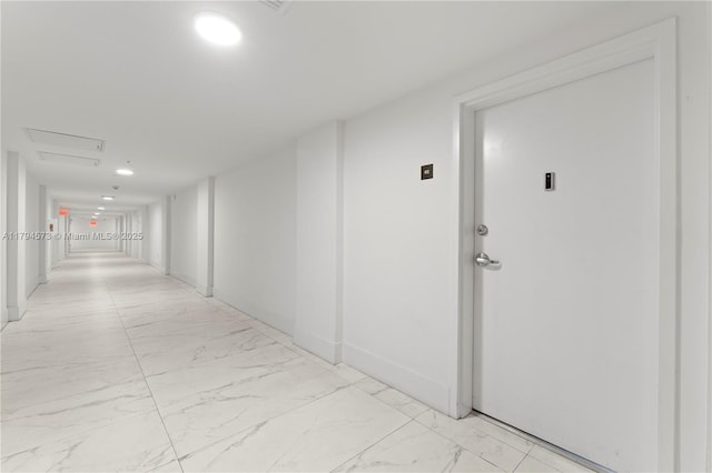 hallway with baseboards and marble finish floor