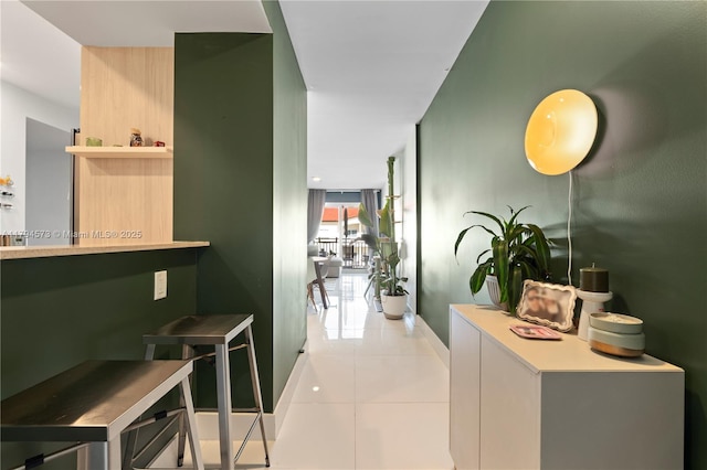 hall with baseboards and light tile patterned floors