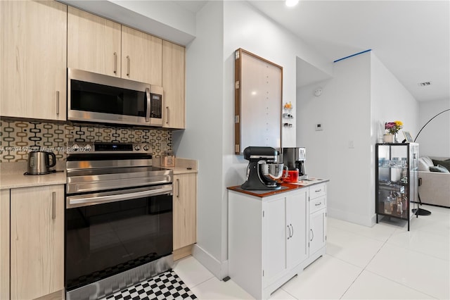 kitchen featuring light brown cabinets, decorative backsplash, stainless steel appliances, and visible vents