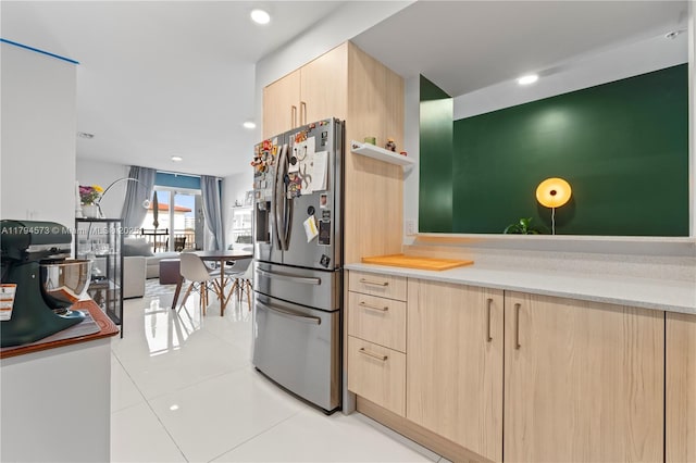 kitchen with stainless steel fridge, light brown cabinets, light countertops, open floor plan, and light tile patterned floors