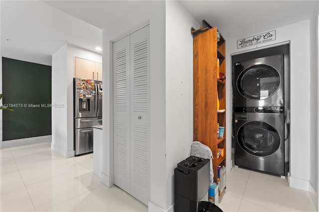 washroom with recessed lighting, stacked washer / drying machine, light tile patterned floors, and laundry area