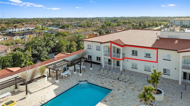 back of property featuring a residential view, a balcony, a tile roof, and a community pool