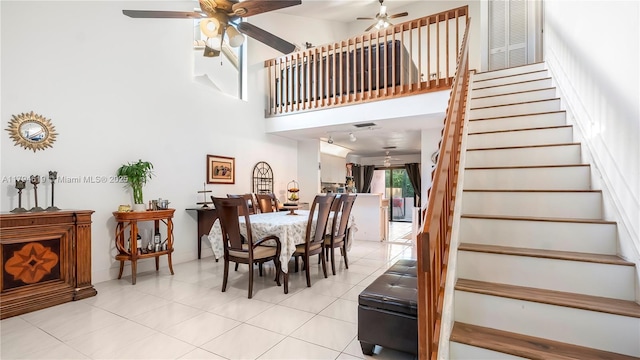 dining space with ceiling fan, a high ceiling, light tile patterned flooring, and stairway