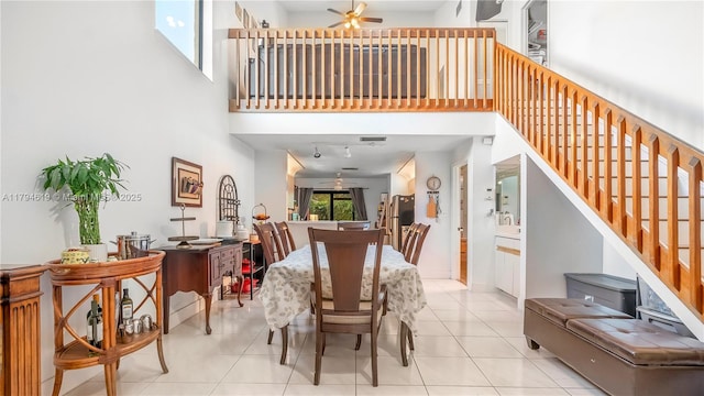 tiled dining area featuring ceiling fan, stairway, and a towering ceiling