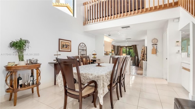 dining area featuring a high ceiling, visible vents, track lighting, and light tile patterned floors
