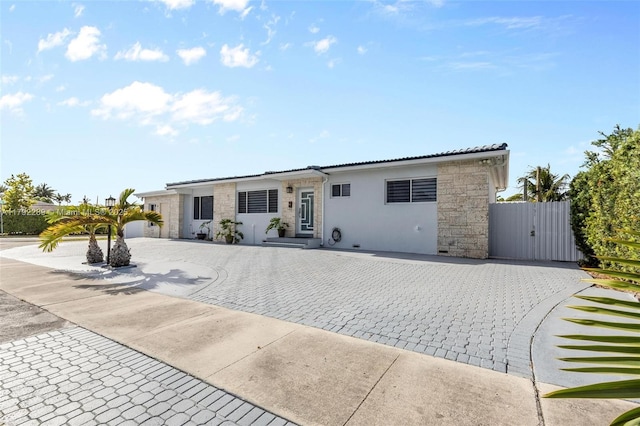 9365 SW 44th St, Miami, FL 33165 - view of front facade with a tiled roof, a gate, decorative driveway, stone siding, and stucco siding