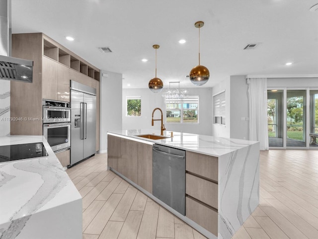 kitchen with appliances with stainless steel finishes, a sink, light wood-style floors, visible vents, and modern cabinets