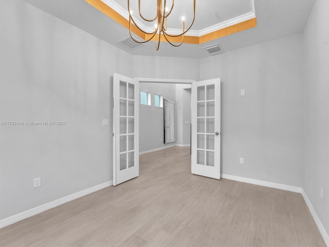 unfurnished room with french doors, visible vents, baseboards, a raised ceiling, and a chandelier