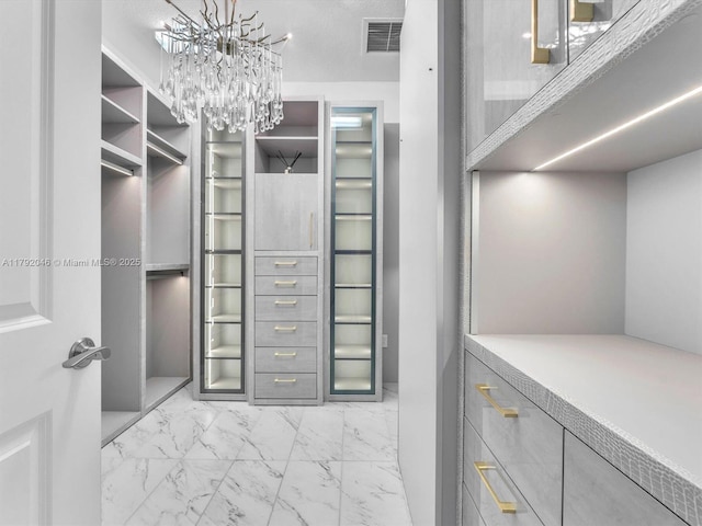 spacious closet with marble finish floor, a chandelier, and visible vents