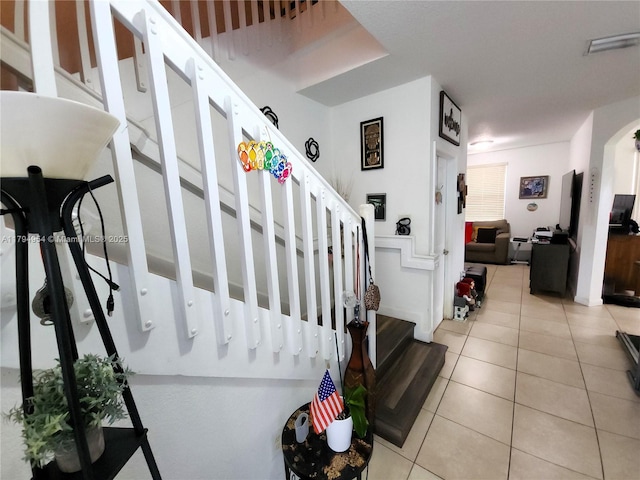 stairs with tile patterned flooring, arched walkways, and visible vents