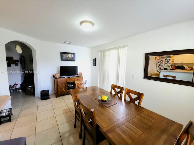 dining space with arched walkways and light tile patterned floors