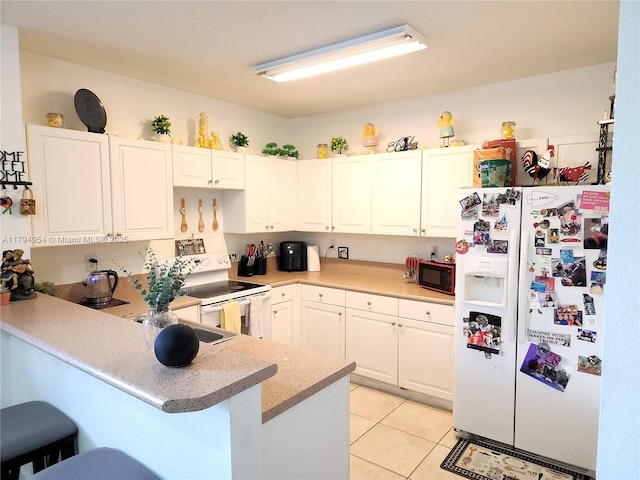 kitchen featuring a breakfast bar area, white appliances, light tile patterned flooring, a peninsula, and white cabinets