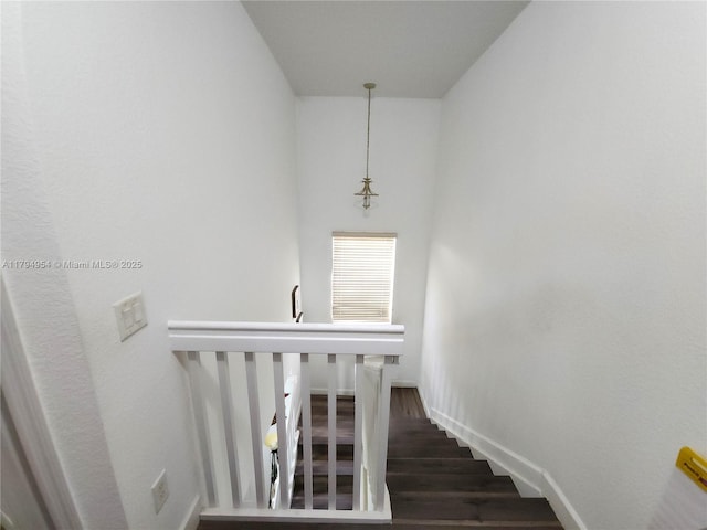 staircase featuring baseboards and wood finished floors