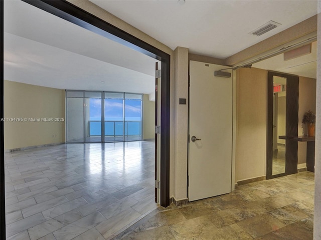 hall featuring visible vents and floor to ceiling windows
