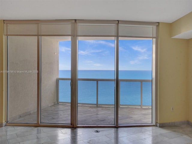 interior space with a water view, floor to ceiling windows, and baseboards