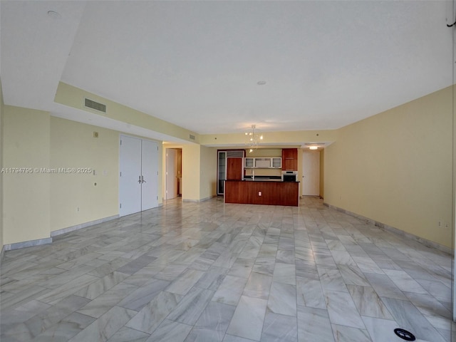 unfurnished living room featuring baseboards, visible vents, and a chandelier