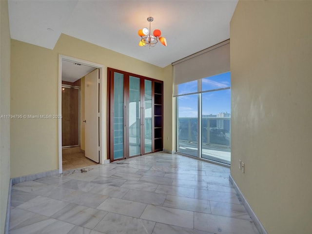 spare room with a notable chandelier and a wall of windows