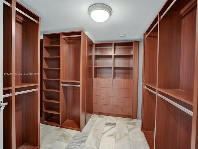 walk in closet featuring marble finish floor
