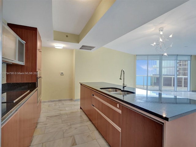 kitchen featuring an inviting chandelier, marble finish floor, modern cabinets, black electric cooktop, and a sink