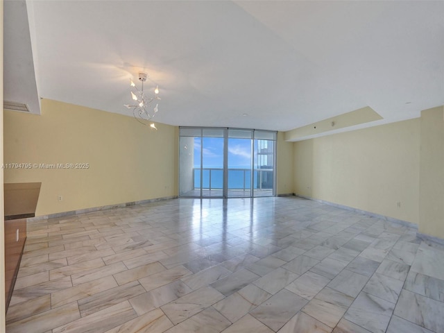 spare room featuring an inviting chandelier and a wall of windows