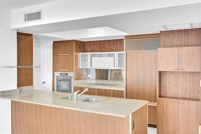 kitchen featuring visible vents, stainless steel oven, modern cabinets, paneled refrigerator, and a sink