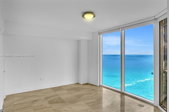 unfurnished room featuring a water view and floor to ceiling windows
