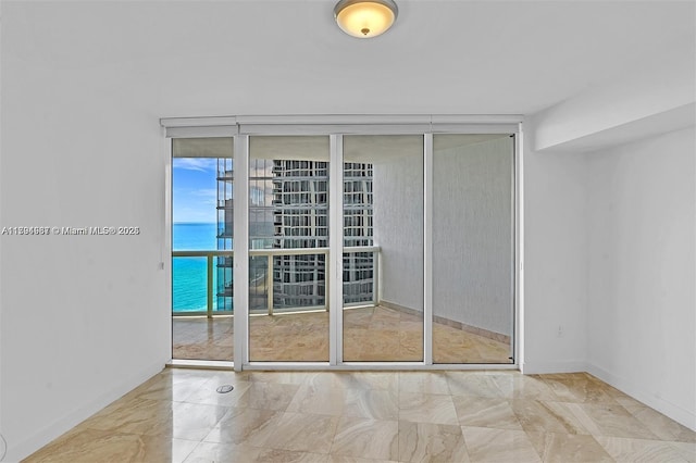 empty room with baseboards and a wall of windows