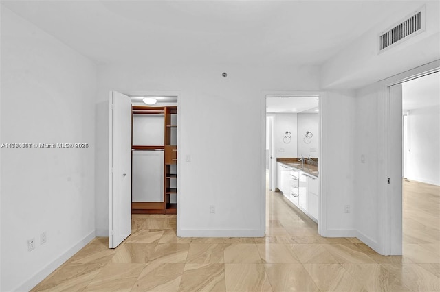 unfurnished bedroom featuring visible vents, a closet, baseboards, a walk in closet, and connected bathroom