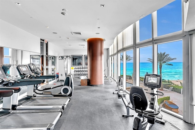 workout area with visible vents, a towering ceiling, and a water view