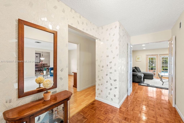 hall with baseboards, wallpapered walls, a textured ceiling, and parquet floors
