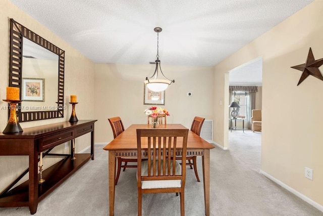 dining room with carpet, a textured ceiling, and baseboards
