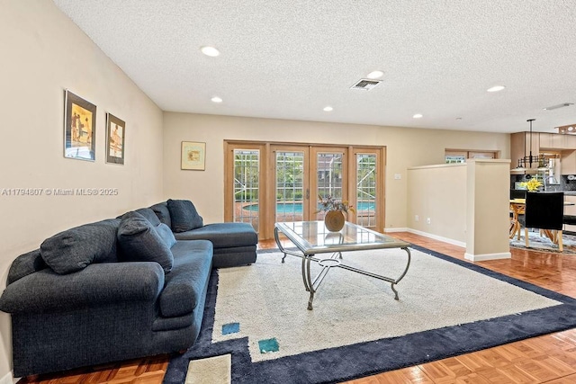 living area featuring a textured ceiling, french doors, visible vents, and recessed lighting