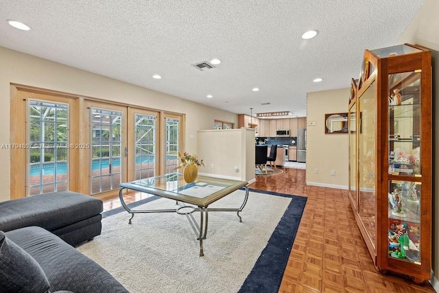 living area with a textured ceiling, plenty of natural light, french doors, and visible vents