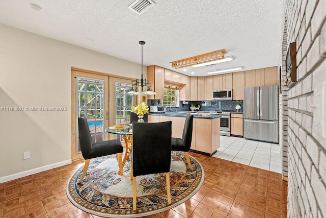 dining area featuring a healthy amount of sunlight, a textured ceiling, and visible vents